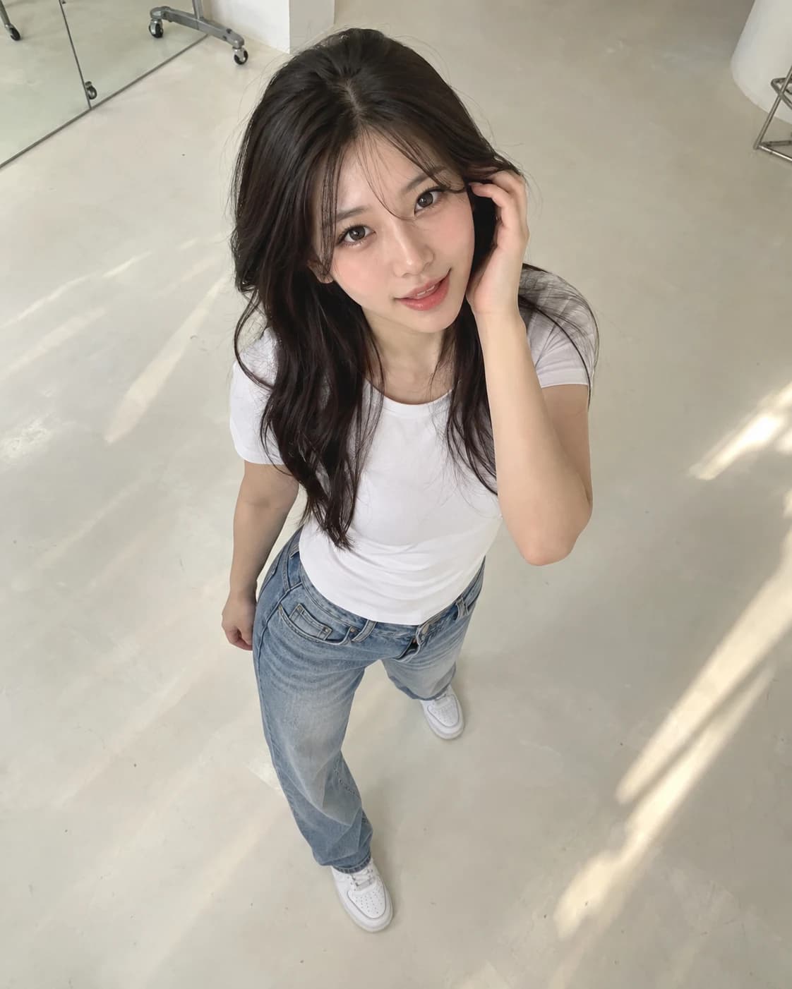 Foto einer Frau von oben, die ein weißes T-Shirt, helle Jeans und Turnschuhe trägt